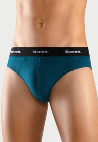 Türkise Baumwollslips mit einem schwarzen elastischen Bund, der mit weißem "Bench." Branding versehen ist. Glatte Textur und taillierte Passform für hohen Tragekomfort.