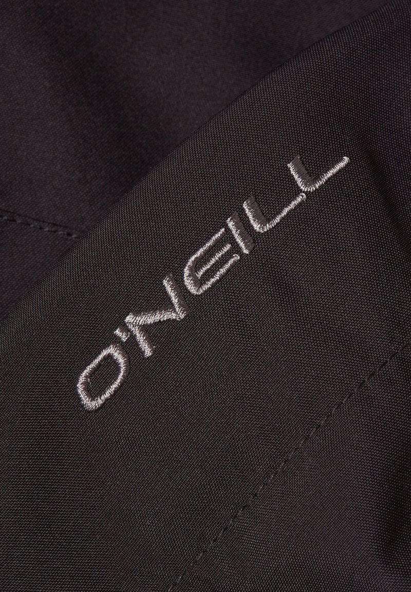 Tela negra con una textura suave, que presenta el nombre de la marca "O'Neill" bordado en hilo plateado. Detalles de diseño simples y modernos.