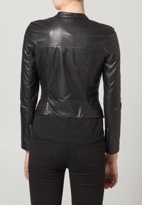Černá kožená bunda s přiléhavým střihem, hladkou texturou a dlouhými rukávy. Má minimalistický límec a zipy na manžetách.