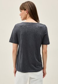 Charcoal gray short-sleeve t-shirt with a subtle leaf pattern, round neck, and relaxed fit. Made of soft, lightweight fabric.