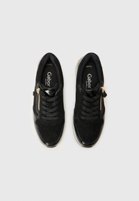 Une paire de baskets Gabor noires avec des lacets et des zips latéraux dorés, présentée de dessus sur un fond blanc.
