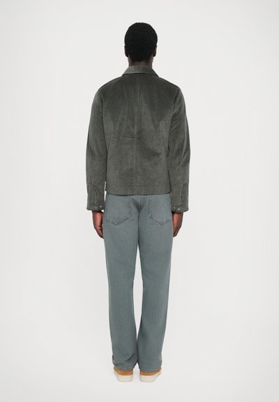 Grå kordfløjljakke med struktureret krave, parret med løse, lysegrå denimjeans og beige sko. Viser et rent rygview.