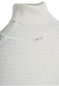 Maglione bianco strutturato con un colletto alto a coste e un dettaglio etichetta argentata, che presenta un motivo distintivo e un tessuto liscio.