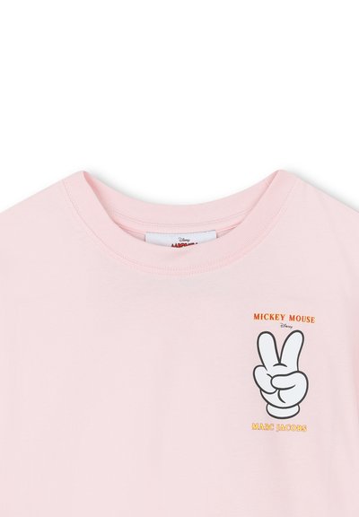 Jasnoróżowa koszulka z nadrukiem dłoni Micky'ego Mouse'a, pokazującej znak pokoju, oraz napisem "Mickey Mouse Marc Jacobs" na piersiach.