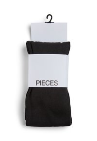 Črne legice ovite v bel trak z oznako "PIECES." Legice imajo gladko teksturo in preprost dizajn, brez vidnih vzorcev.