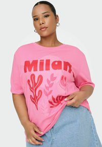 Camiseta de algodón rosa con "Milán" en texto rojo en negrita, acompañada de gráficos de hojas y plantas en diferentes tonos de rojo, combinada con una falda de mezclilla clara.