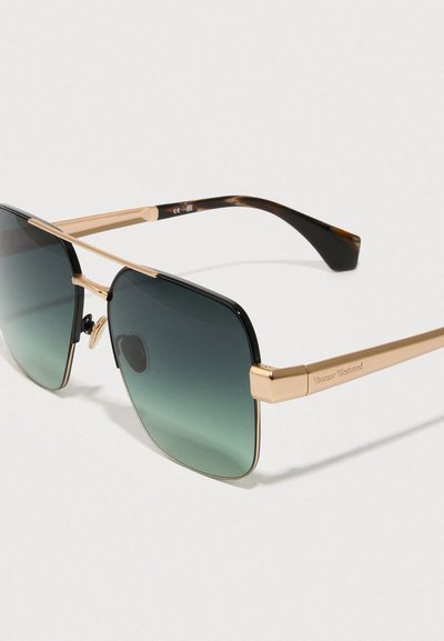 Óculos de sol de armação quadrada com detalhes em metal dourado, lentes escuras com transição para um leve gradiente e padrão de tartaruga nas hastes.