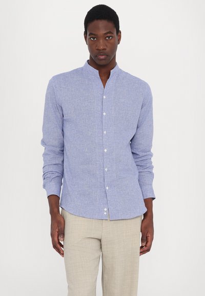 Camicia azzurro chiaro a maniche lunghe con colletto alla cinese, caratterizzata da un sottile motivo testurizzato e chiusura con bottoni, abbinata a pantaloni beige.