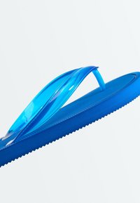 Une sandale tong bleue unique avec des brides translucides bleues, présentée en angle sur fond blanc.