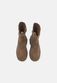 Paire de bottines en daim marron avec fermetures éclair latérales et bouts ronds, vues de dessus sur fond blanc.
