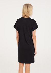 Schwarzes T-Shirt-Kleid mit lockerer Passform, kurzen, umgeschlagenen Ärmeln und rundem Halsausschnitt. Weicher Stoff ohne Muster oder Verzierungen.