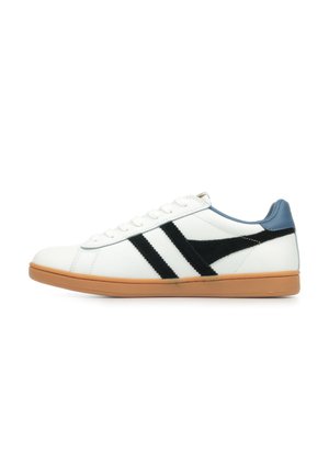 Zapatilla blanca con rayas de ante negro, acento azul en el talón y suela de goma marrón. Presenta un diseño clásico de cordones.