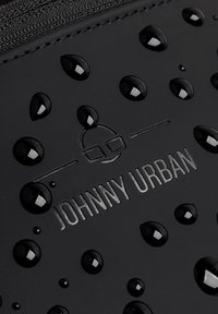 Waterproof black material with raised water droplets and embossed 'JOHNNY URBAN' logo. Smooth texture, minimalist design, and circular accents.