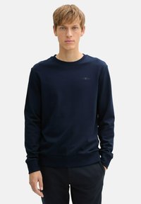Marineblaues Langarm-Sweatshirt aus weichem Stoff, mit einem gerippten Rundhalsausschnitt und Bündchen, und einem kleinen Logo auf der Brust.