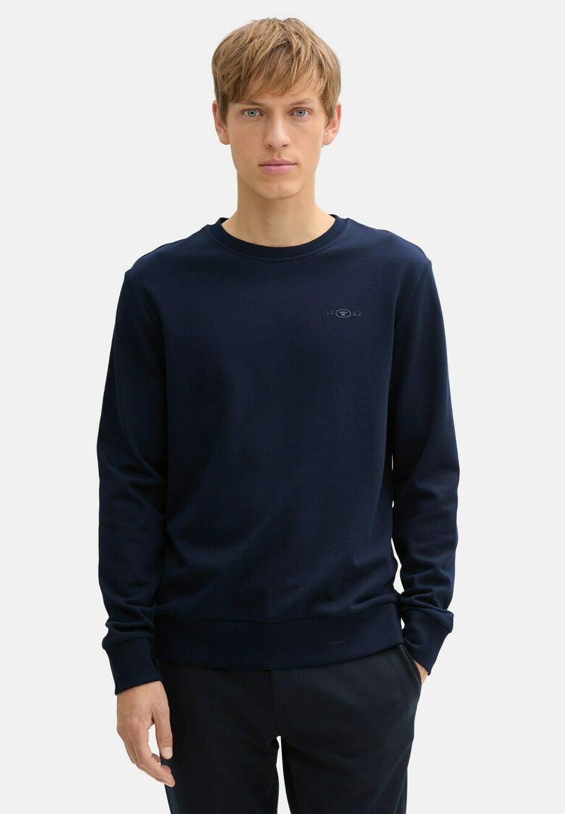 Marineblaues Langarm-Sweatshirt aus weichem Stoff, mit einem gerippten Rundhalsausschnitt und Bündchen, und einem kleinen Logo auf der Brust.
