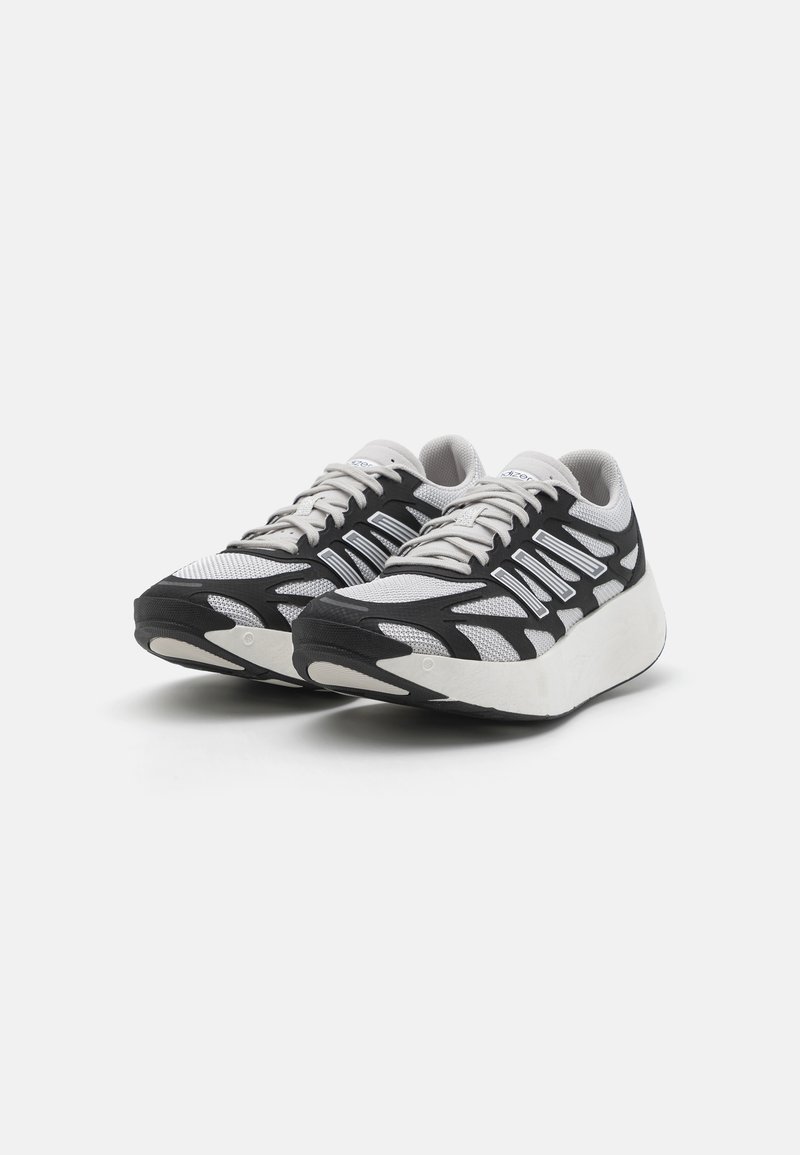 Scarpe sportive in bianco e nero con una tomaia in rete, dettagli testurizzati e una suola intermedia spessa bianca. Presentano un design con lacci e una suola in gomma.
