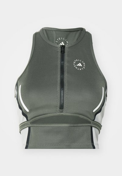 Top corto deportivo verde hecho de tejido elástico, con cremallera frontal, diseño ligero, acentos blancos y un logo redondo.