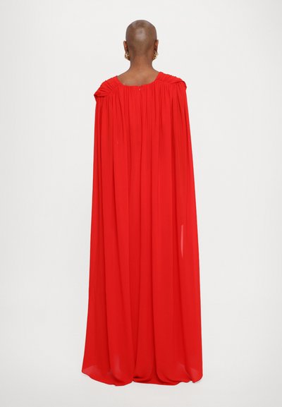 Red flowing cape dress made of lightweight fabric, featuring gathered detailing at the shoulders and a loose fit, extending to the floor.