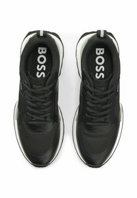 Sneakers stringate in bianco e nero con dettagli in mesh e pelle, brandizzate "BOSS" sulle solette e sui lati, viste dall'alto.