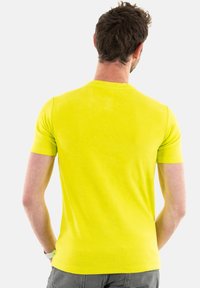 T-shirt à manches courtes et col rond de couleur jaune néon vive, fabriqué en tissu doux avec une texture lisse. La vue de dos montre un design ajust�é.