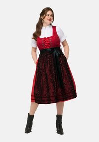 Robe dirndl rouge et noire avec superposition de dentelle florale, corsage ajusté, blouse blanche et ceinture en nœud noir. Comprend des lacets de style corset et des poches.