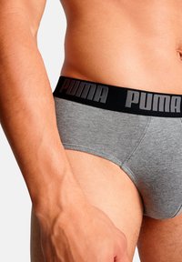 Graue Herrenunterhosen mit einem schwarzen elastischen Bund, auf dem ein erhabenes "PUMA"-Logo zu erkennen ist. Das Material wirkt weich und dehnbar und sorgt für eine bequeme Passform.