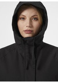 Czarna, kapturowa kurtka o gładkim, matowym wykończeniu. Posiada wysoki kołnierz i regulowane sznurki przy kapturze, zapewniające dopasowanie.
