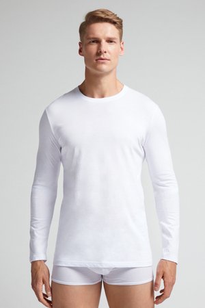 Chemise blanche à manches longues en tissu lisse, avec un col rond et une silhouette ajustée, assortie �à des sous-vêtements blancs.