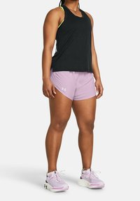 Svart atletisk tanktopp med gröna detaljer, kombinerad med ljuslila shorts med en logotyp. Vita och lila löparskor fulländar looken.