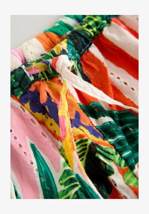 Zbliżenie na kolorową, wzorzystą tkaninę z zawiązanym sznurkiem i ozdobnymi oczkami.