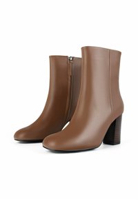 Bruine leren enkelboots met een gladde textuur, een ronde neus en een zijrits. Ze hebben een houten blokhak voor extra lengte.