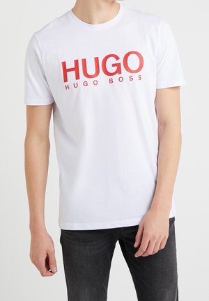 Biała bawełniana koszulka z krótkim rękawem z wyraźnym czerwonym napisem „HUGO” i „HUGO BOSS” nadrukowanym z przodu. Standardowy krój.