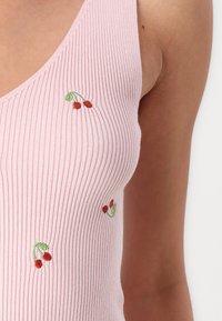Różowy top na ramiączkach z prążkowanej tkaniny, ozdobiony haftowanymi motywami wiśni w kolorze czerwonym i zielonym. Materiał ma miękką fakturę i dopasowany krój.