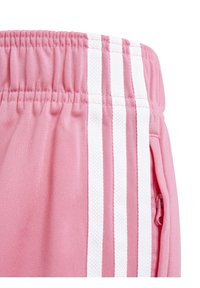 Pink athletic shorts featuring a textured elastic waistband, white side stripes, and a zippered pocket detail on the side.