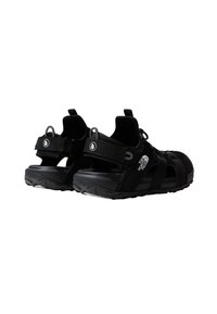 Black sandals with a textured upper, adjustable straps, and a rubber sole. Features include a heel loop and logo accents on the side.
