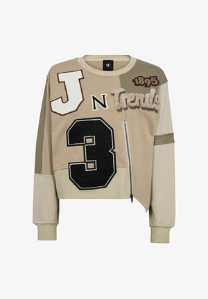 Felpa corta beige con lettere e numeri in applicazione testurizzata, dettaglio con zip e pannelli di tessuto di diverse tonalità.