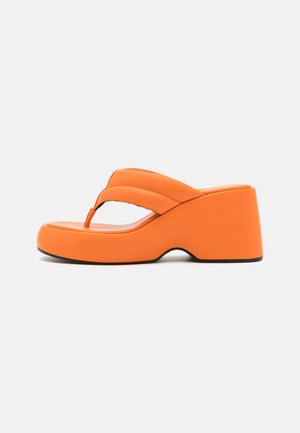 Oranje platform sandalen met een dikke hak, voorzien van een brede band en teenpostontwerp. Gladde textuur, minimale details en ronde vorm.