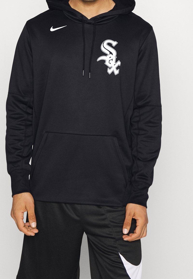 Sweat à capuche Nike noir avec logo blanc des Chicago White Sox sur la poitrine, porté avec un pantalon Nike noir avec un grand Swoosh blanc.