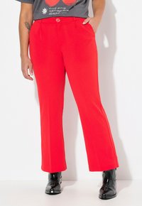 Pantalons rouges évasés en tissu lisse. Dotés d'une fermeture à bouton à la taille, de poches latérales en biais et d'une coupe ajustée.