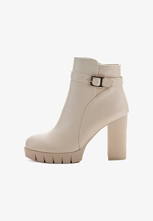 Beige Knöchelstiefel aus Kunstleder mit hohen Blockabsätzen, strukturiertem Sohlen, geschwungenem Design und einem Riemen mit einem metallischen Schnallendetail.