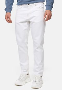 Jeans de denim blanco con costuras visibles, diseño de ajuste slim, estilo de cinco bolsillos, usados con zapatillas blancas. Textura suave, aspecto clásico y casual.