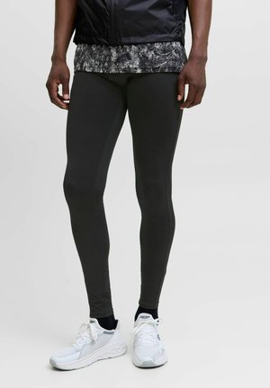 Zwarte sportleggingen van rekbaar materiaal, aansluitend ontwerp, gladde textuur, met contrasterende naden en gecombineerd met witte sneakers.