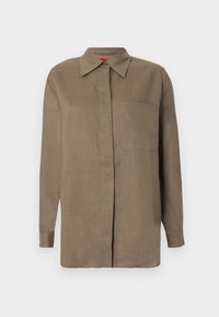 Κοντομάνικο καφέ πουκάμισο με κουμπιά, με μυτερό γιακά και μία τσέπη στο στήθος, εμφανίζεται σε απλό φωτεινό φόντο.