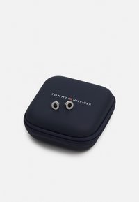 Estuche para pendientes de Tommy Hilfiger, de concha dura azul marino con pendientes en tono plateado de diseño redondo y acentos texturizados. Cierre con cremallera.