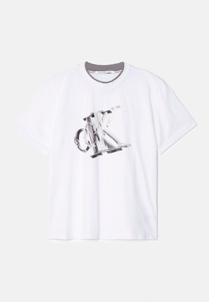 T-shirt en coton blanc à manches courtes, avec un grand logo graphique "CK" en gris et noir sur le devant ; encolure ronde avec un bord gris.