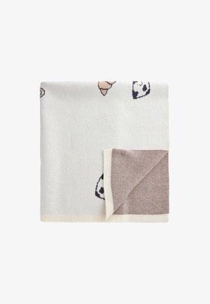 Gefaltete weiße Strickdecke mit kleinen Hundegesichtsmustern und einer Ecke, die umgeklappt ist, um die beige strukturierte Rückseite zu zeigen.