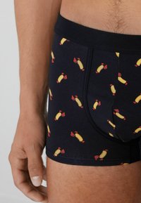 Pánské boxery ve tmavě modré barvě s opakujícím se vzorem hot dogů a humrů. Měkký, elastický materiál s pohodlným pasem.