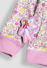 Stoff mit Blumenmuster in Rosa und Gelb. Verfügt über einen aufgestickten Feen-Patch mit Flügeln an einem hellrosa Bündchen. Weiches Textilmaterial.