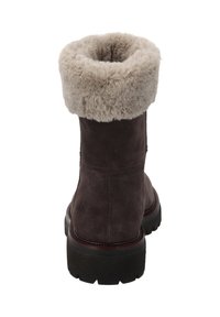 Bruine suède winterlaars met beige pluizige bontmanchet en dikke zwarte profielzool, gezien van de achterkant op een witte achtergrond.