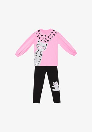 Pink bluse med lange ærmer med et smilende hvidt leopardtryk og sorte pletter, parret med sorte bukser med en lille matchende hvid leopardapplikation.